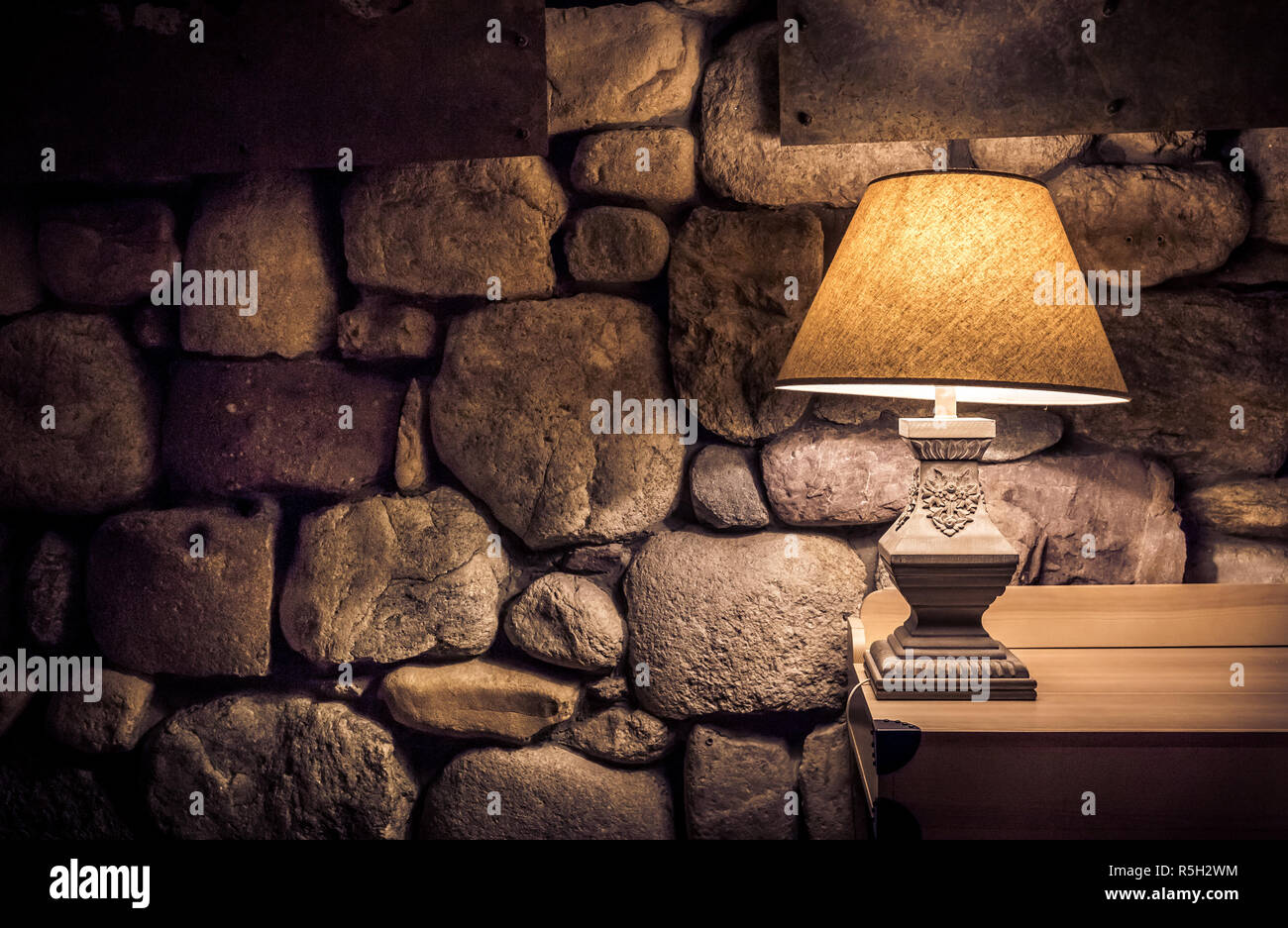 Mur de pierre éclairés par la lampe sur table en bois élégant Banque D'Images