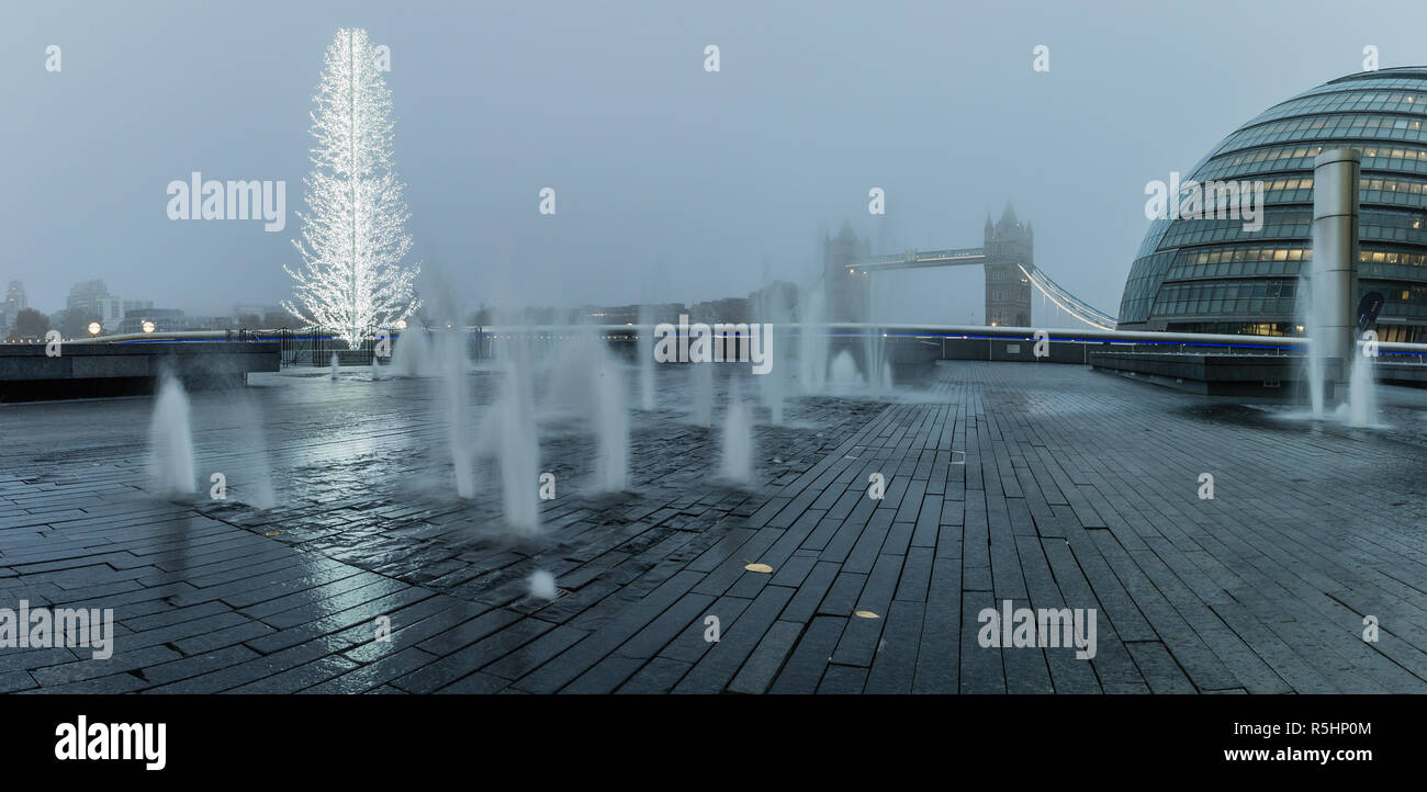 La vue panoramique de l'Hôtel de Ville et le Tower Bridge dans le brouillard pendant la saison de fête à Londres. Banque D'Images