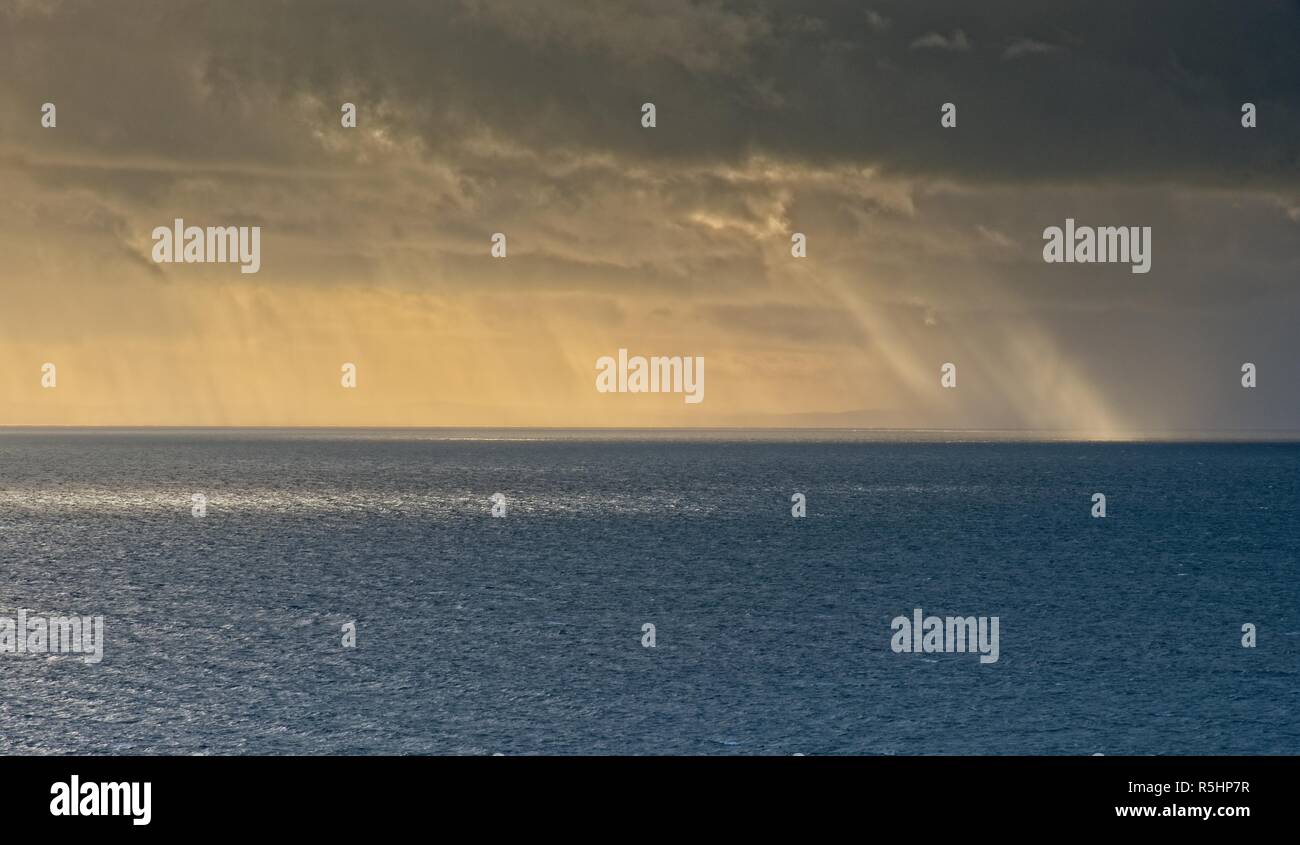 La pluie et du soleil tombant dans la mer d'Irlande, comme vu de Mynydd Cilan, près de Abersoch, Gwynedd, Pays de Galles Banque D'Images