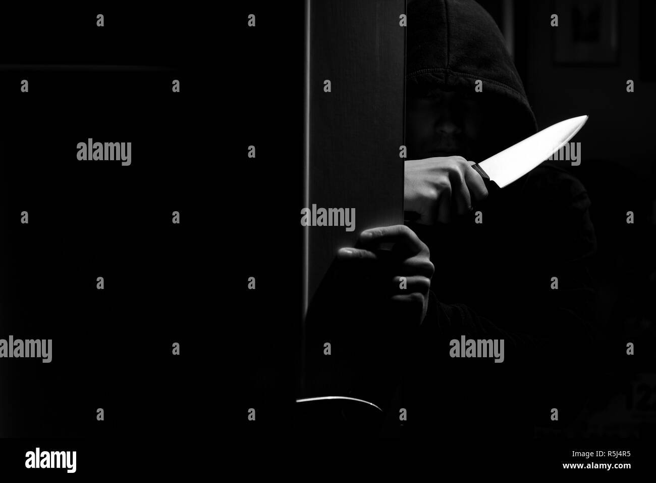 Photo en noir et blanc de killer avec couteau en appartement sombre Banque D'Images