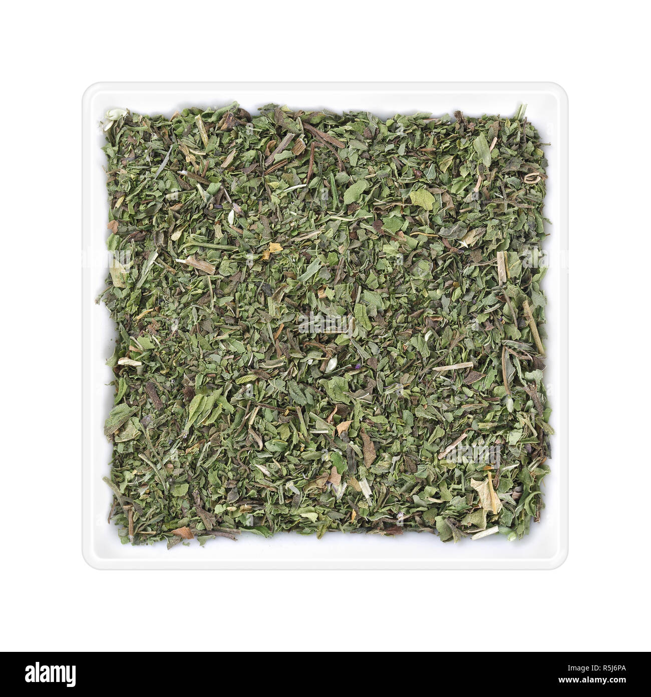 Menthe séchée dans bol carré sur fond blanc Banque D'Images