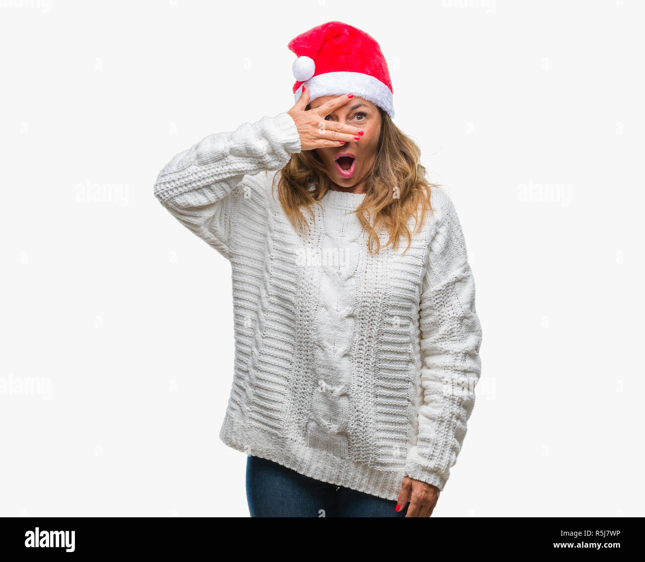 L'âge moyen senior hispanic woman wearing christmas hat sur fond isolé avec des pics de shock couvrant le visage et les yeux avec la main, à la fin de Banque D'Images