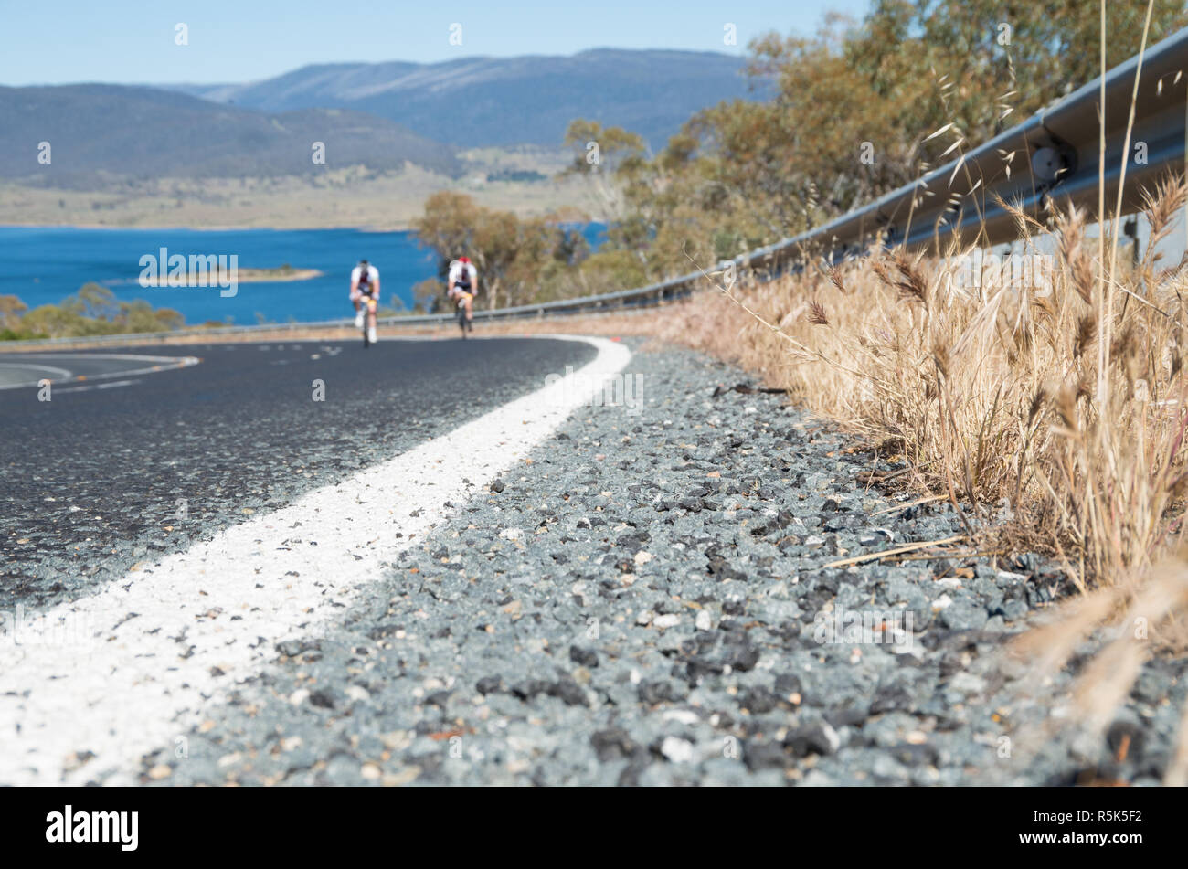 Low angle près d'une route avec deux coureurs de fond dans le passé d'équitation un lac Banque D'Images