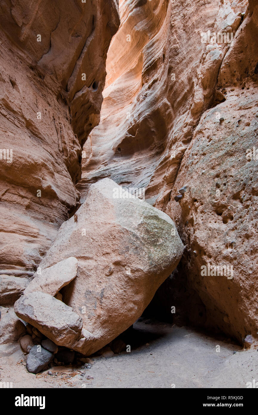 Un énorme rocher se trouve dans le fond d'un profond canyon fente underheath une paroi du canyon reflétant la lumière du soleil d'en haut à Kasha-Katuwe Tent Rocks National Mo Banque D'Images