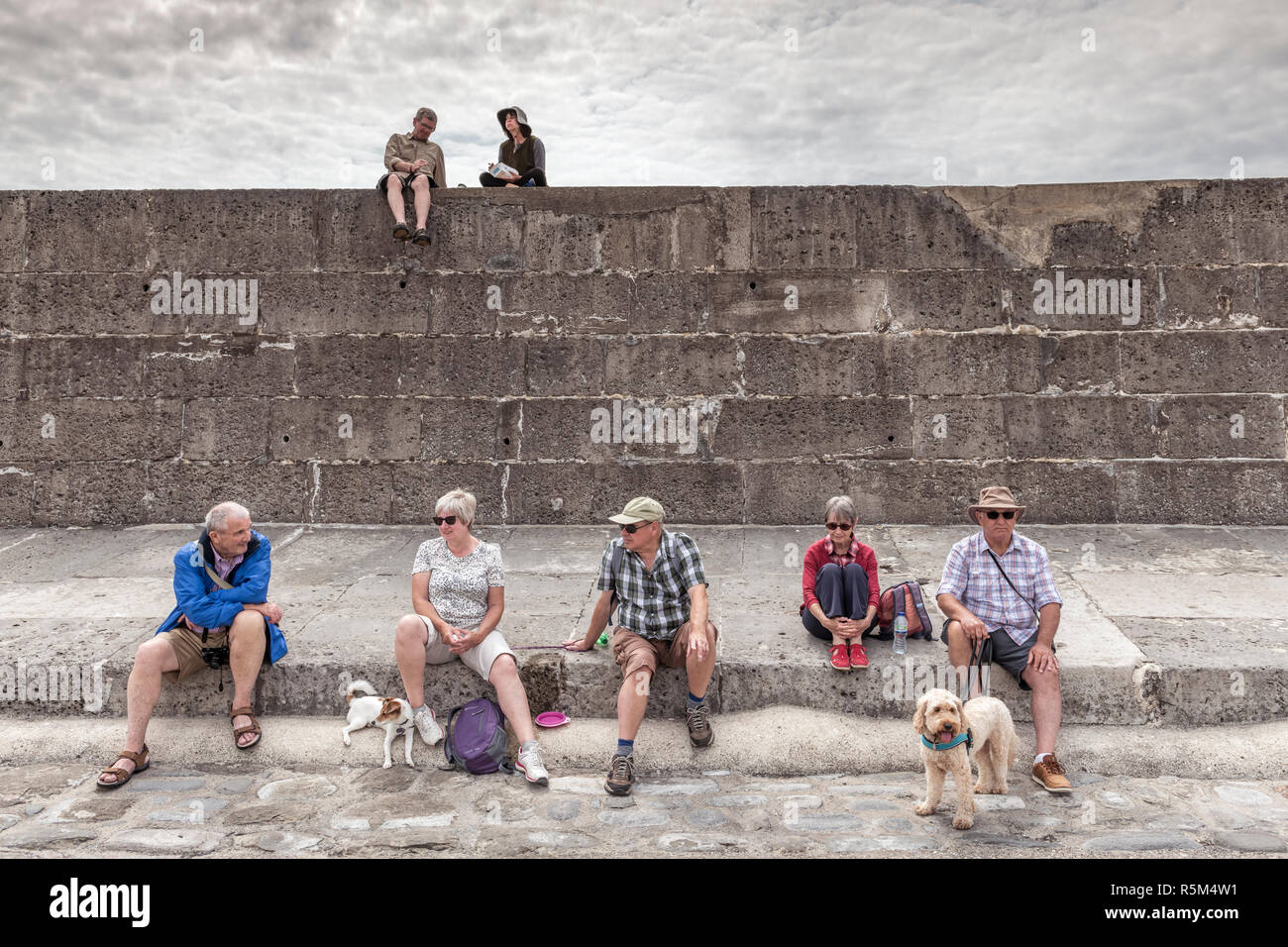 Un groupe de touristes profiter d'un chat sur le Cobb à Lyme Regis dans le Dorset. Banque D'Images