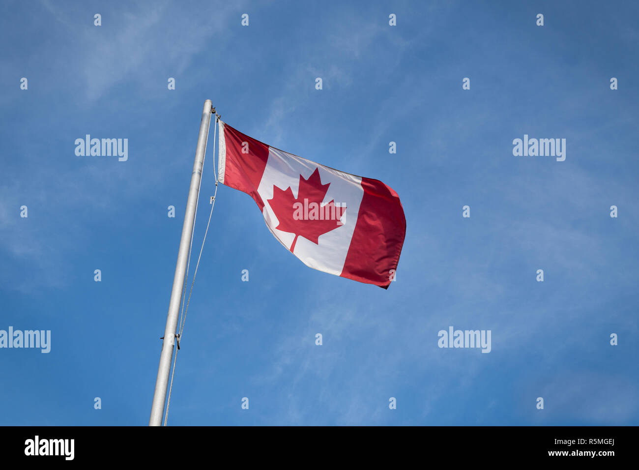 En agitant le drapeau canadien contre le ciel bleu. Banque D'Images