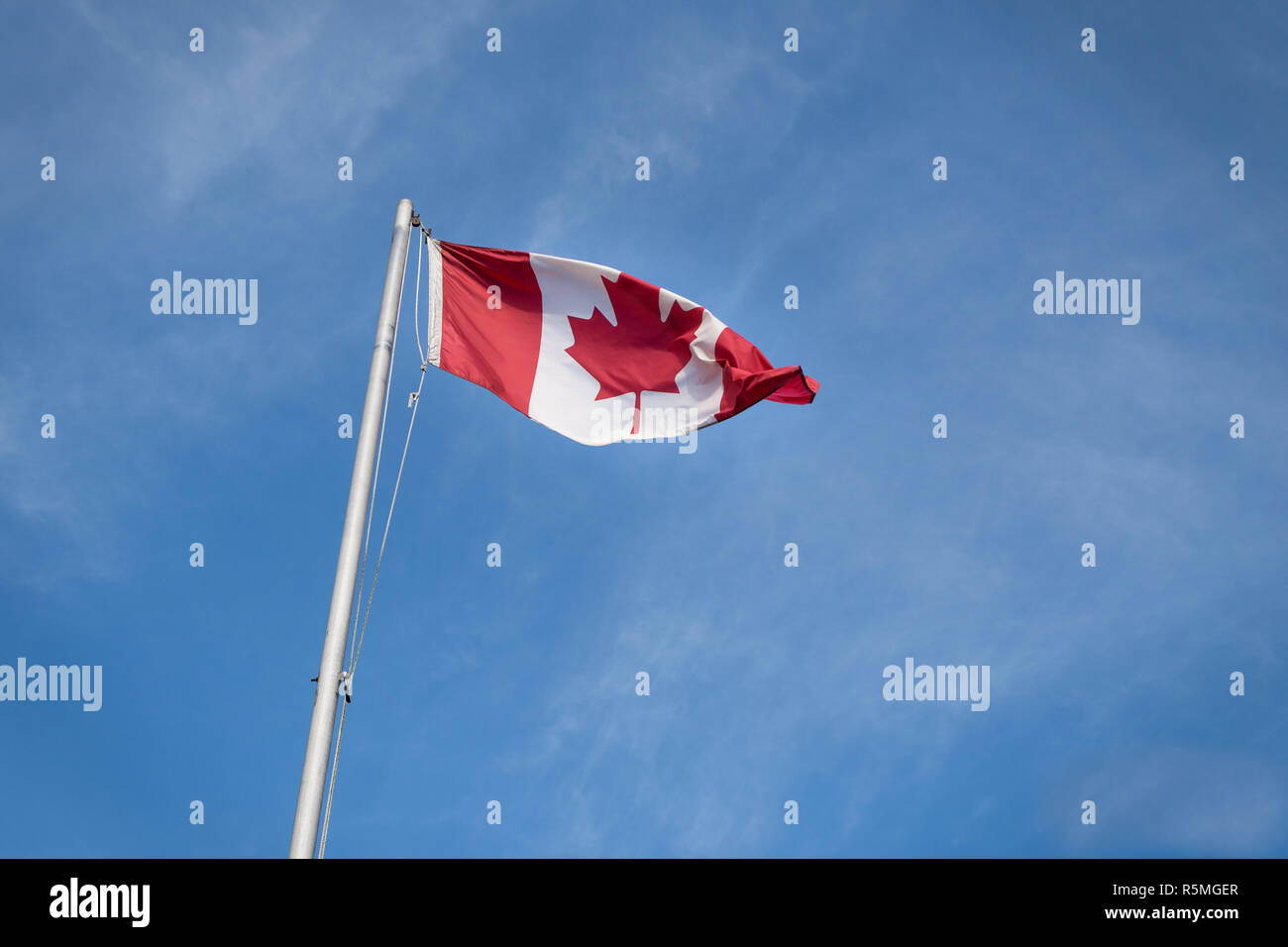 En agitant le drapeau canadien contre le ciel bleu. Banque D'Images