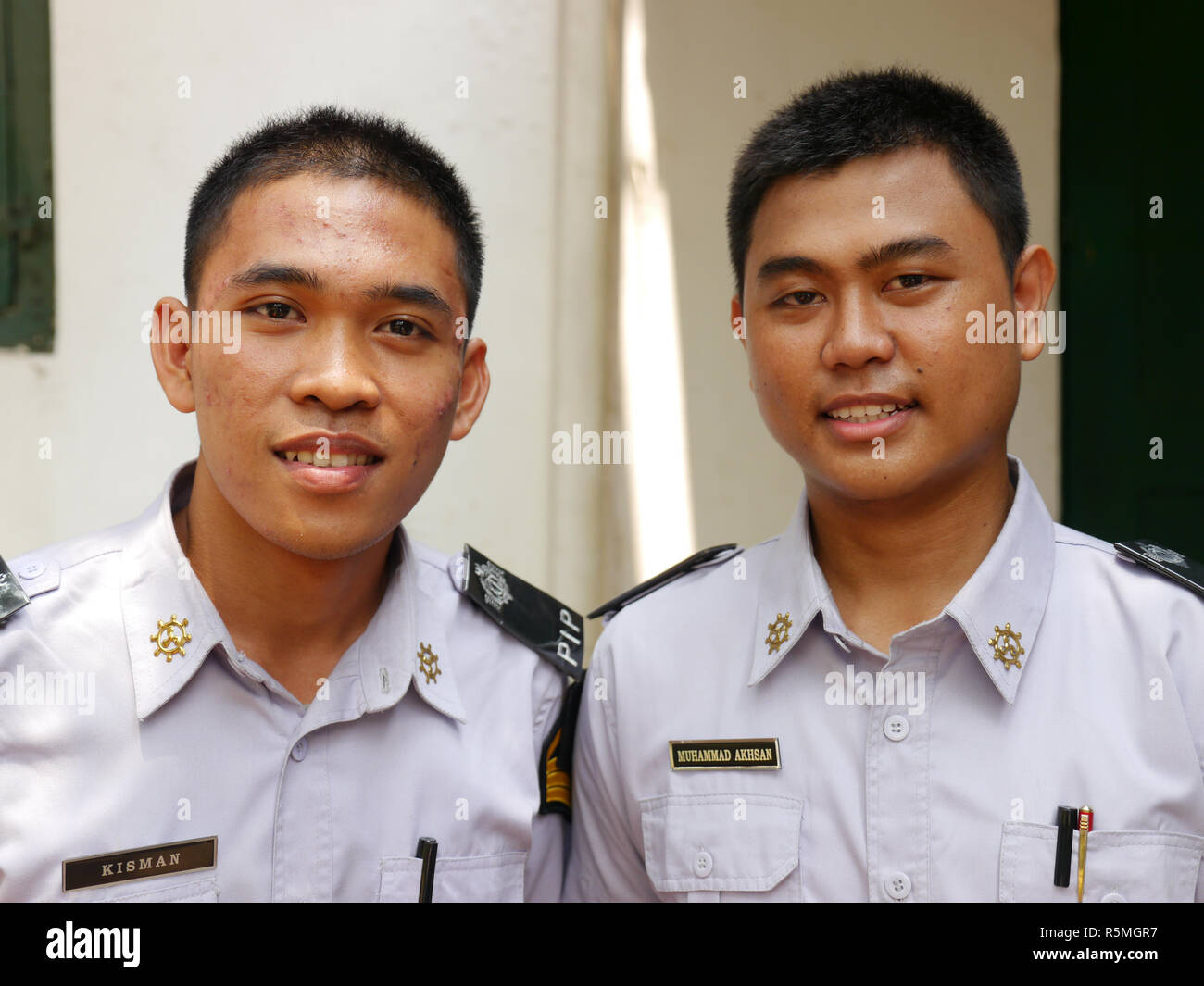 Portrait vertical de jeunes cadets de la marine indonésienne souriant en uniforme à directement à l'appareil photo. Banque D'Images
