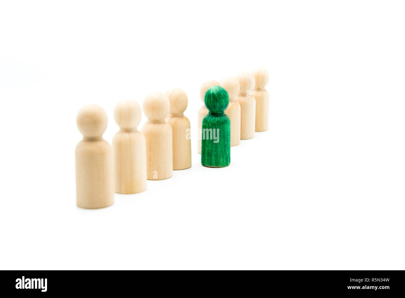 Figures en bois en ligne que l'équipe d'affaires, avec un vert figure debout de la foule, isolé sur fond blanc. Image conceptuelle d'être di Banque D'Images