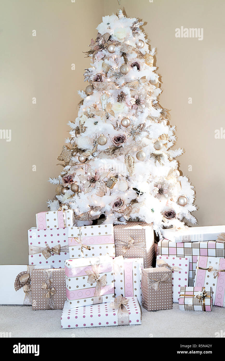 Rêve Blanc arbre de Noël dans la salle de séjour de maison décorée en rose tendre populaires des ornements et les cadeaux ci-dessous correspondant au papier d'emballage. Banque D'Images