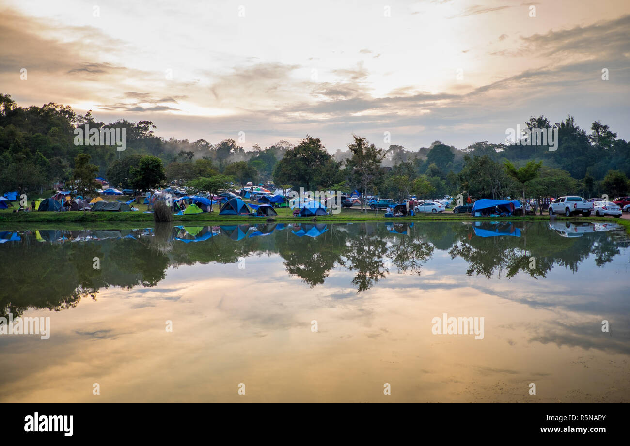 Beaucoup de tentes de camping sur site en Thaïlande et la réflexion sur la surface de l'eau dans l'étang quand le soir au coucher du soleil. Banque D'Images