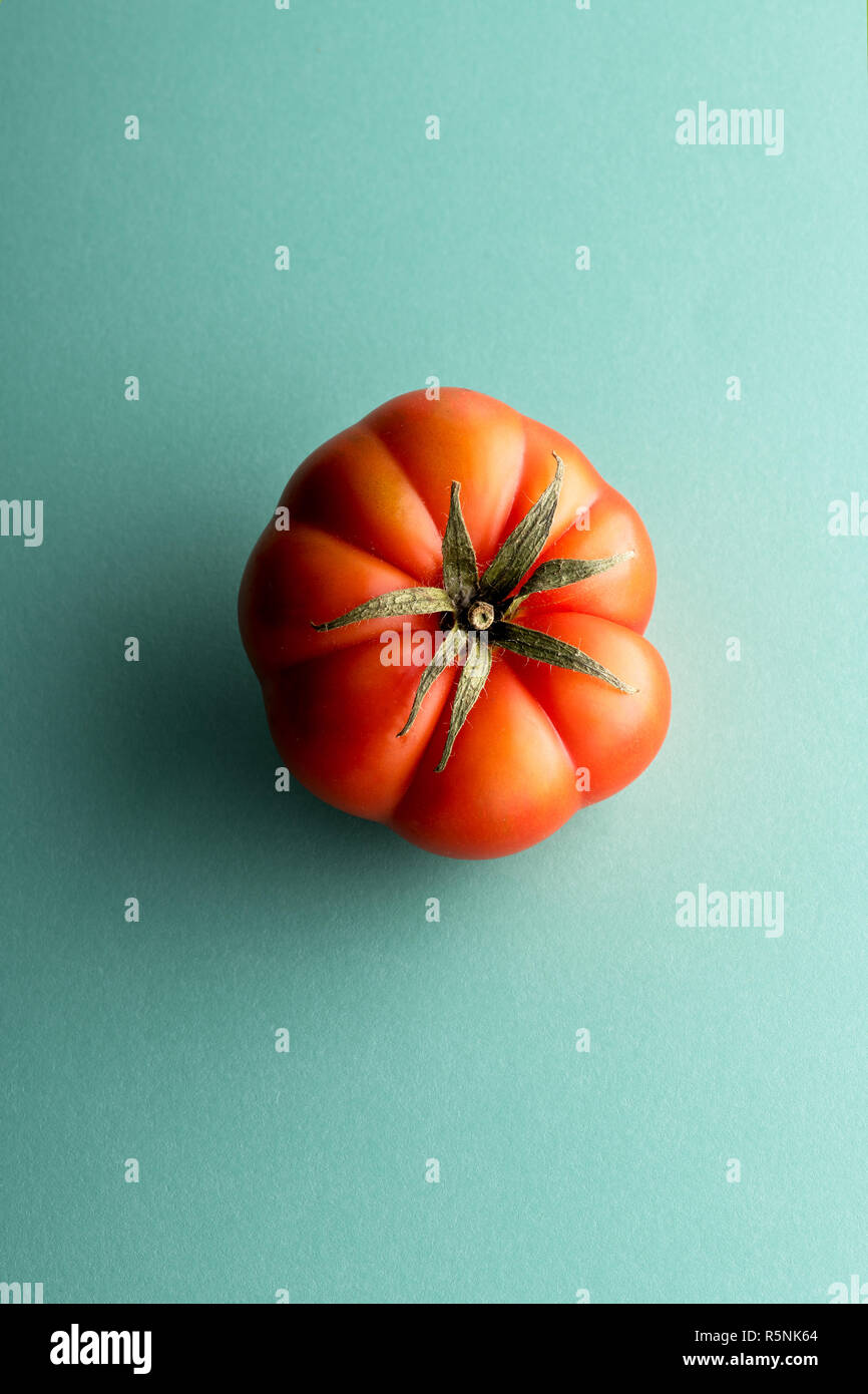 Toute une tomate rouge mûre vue d'en haut au centre sur fond cyan Banque D'Images