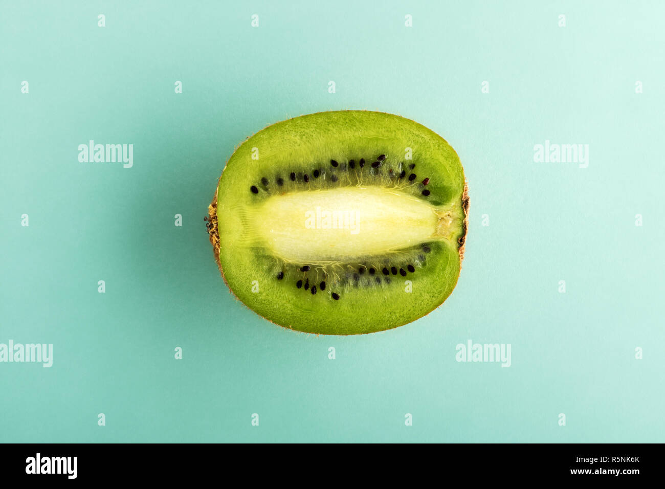 La moitié des kiwis verts mûrs isolés dans le centre de fond cyan. Vue de dessus en close-up Banque D'Images