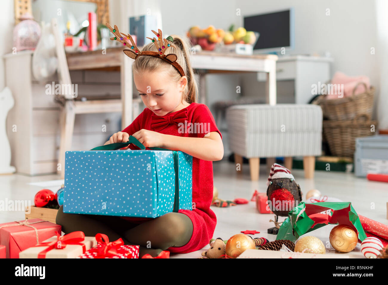 Super cute heureux jeune fille grande ouverture cadeau de Noël tout en  étant assis sur le plancher du salon. Temps de Noël famille candide  contexte de vie Photo Stock - Alamy