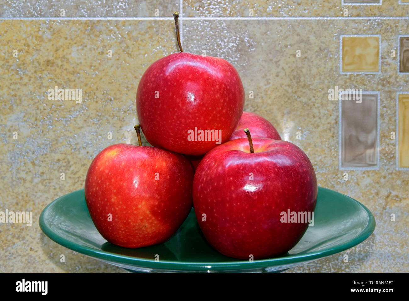 Cireuse, white-spotted pommes rouges de variété Gala empilés sur une plaque verte, haut-latérale vue rapprochée avec arrière-plan géométrique abstraite Banque D'Images