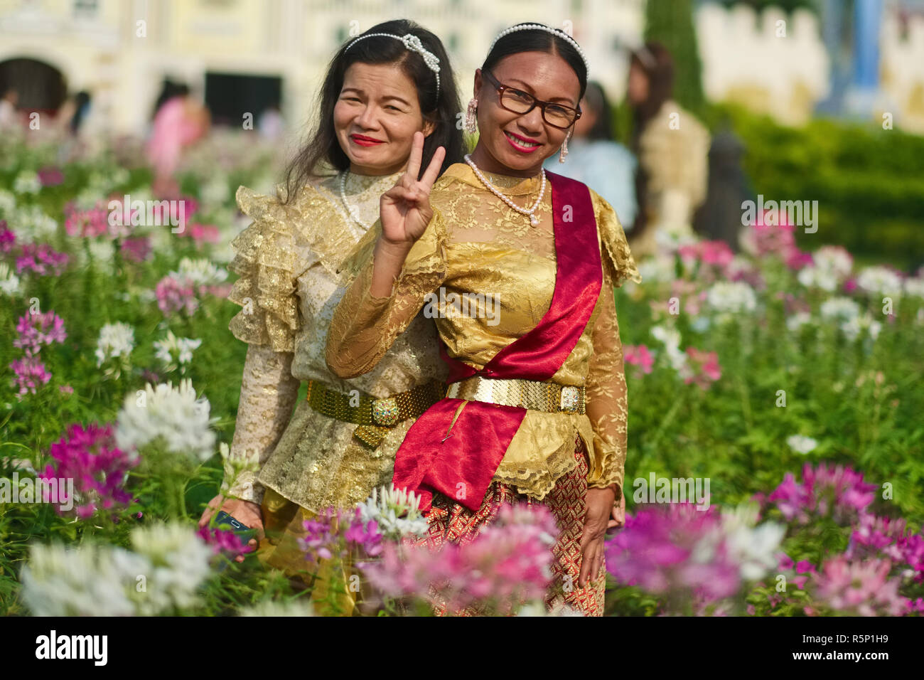 Visiteurs à un événement à la mémoire du roi décédé Bhumipol Adulyadej à Bangkok, Thaïlande, vêtus de costumes traditionnels thaïlandais et clignotant le V-signe Banque D'Images