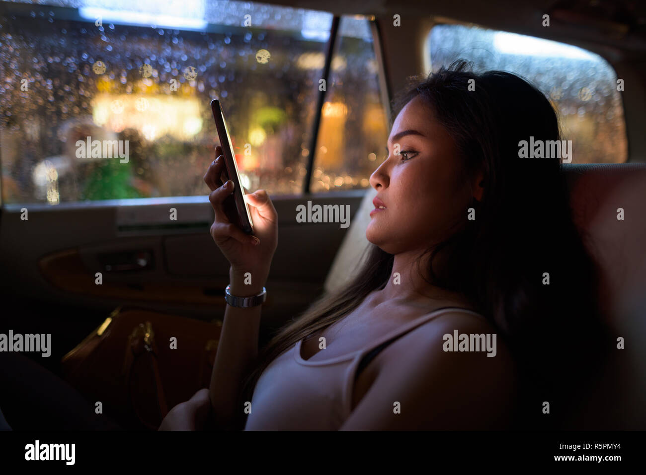 Belle Jeune femme assise dans une voiture de taxi pendant l'utilisation de téléphone mobile dans la nuit Banque D'Images