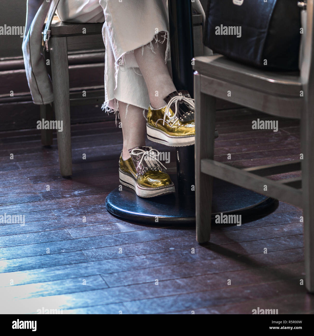 Jeune femme avec des chaussures d'or dans un café. Banque D'Images