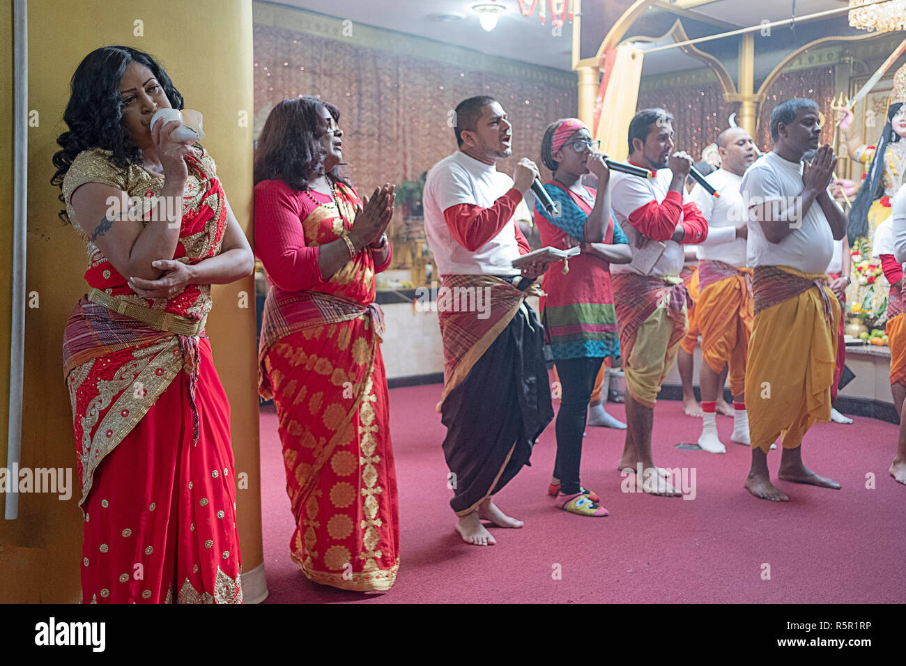 Les fidèles priant et chantant comme une femme souffle dans une conque. Dans le Queens, New York. Banque D'Images
