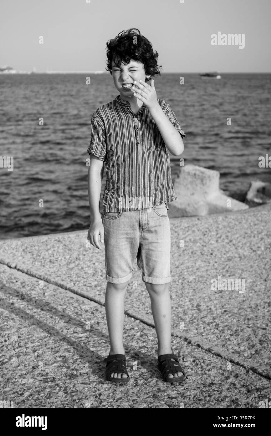 Un garçon est debout près de la mer. Noir et blanc. Banque D'Images