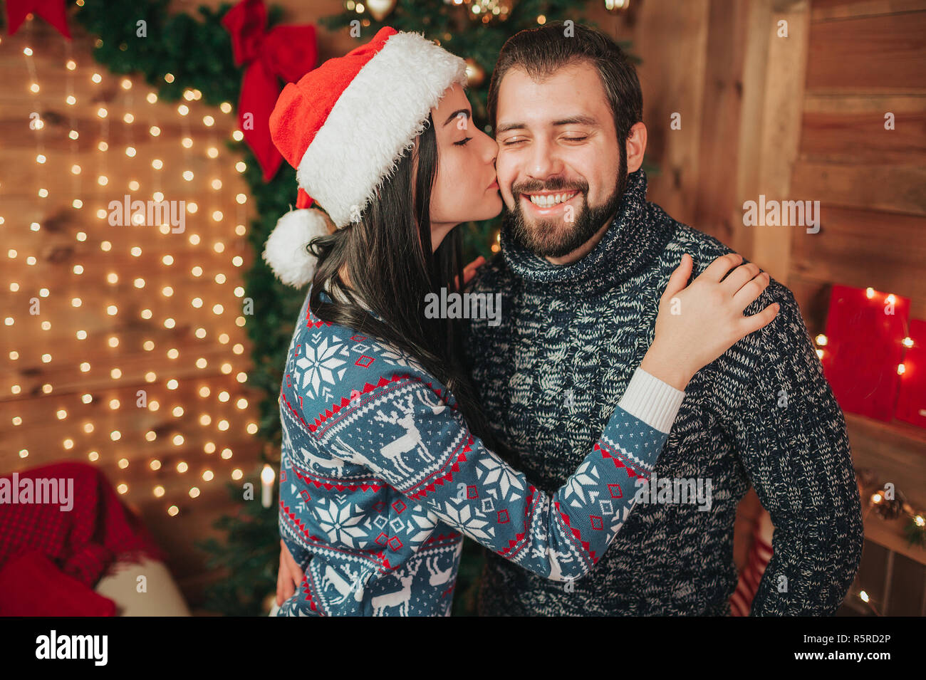 Joyeux Noël et Bonne Année . Les jeunes couples célébrant maison de vacances à la maison. Une jeune femme embrasse un jeune homme barbu sur la joue Banque D'Images