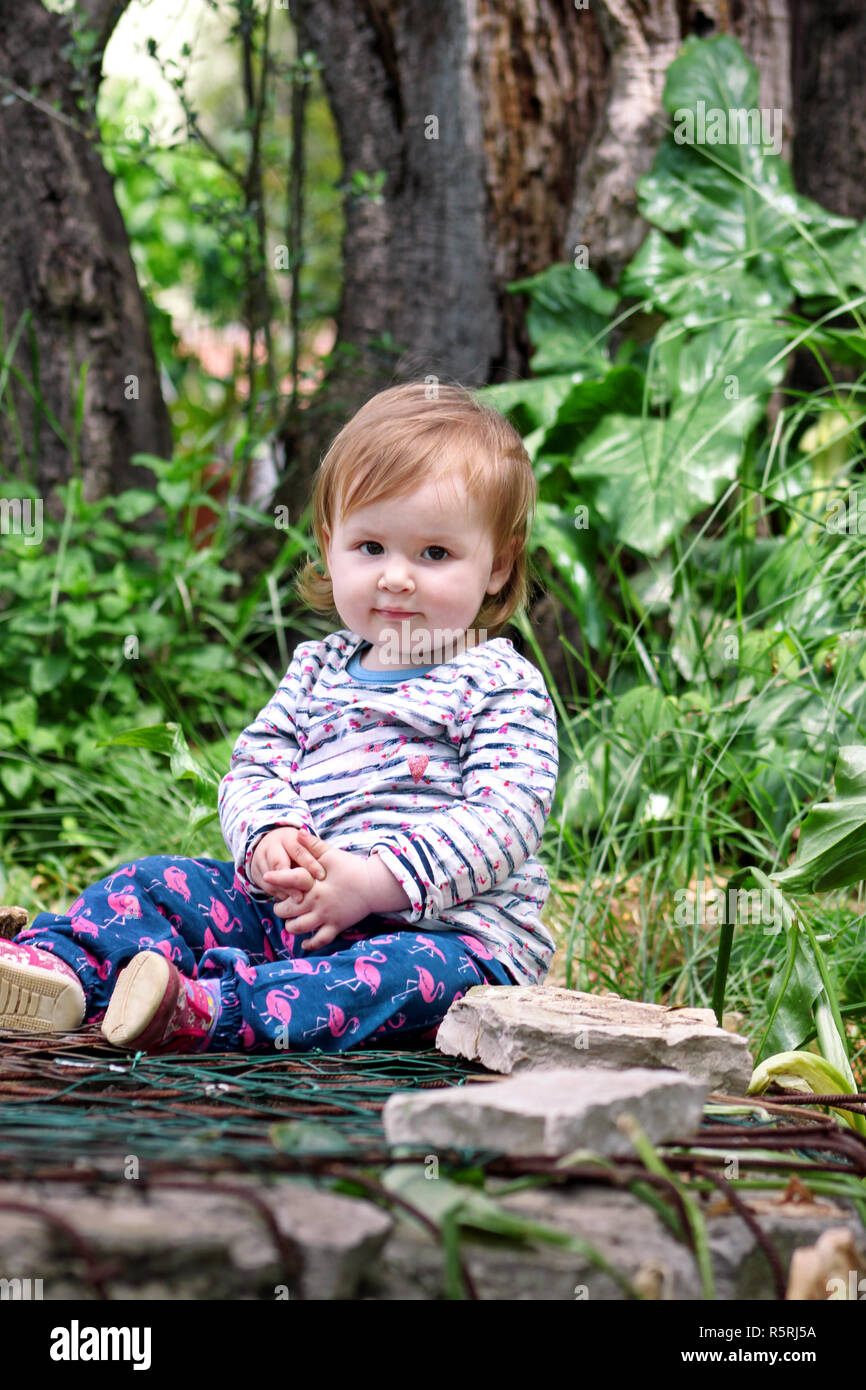 Beau Bebe Assis Souriant Et Posant Portrait Petite Fille Mignonne Est Ludique Dans Le Jardin Enfant Joue Dehors En Parc Entoure Par De Beaux Photo Stock Alamy