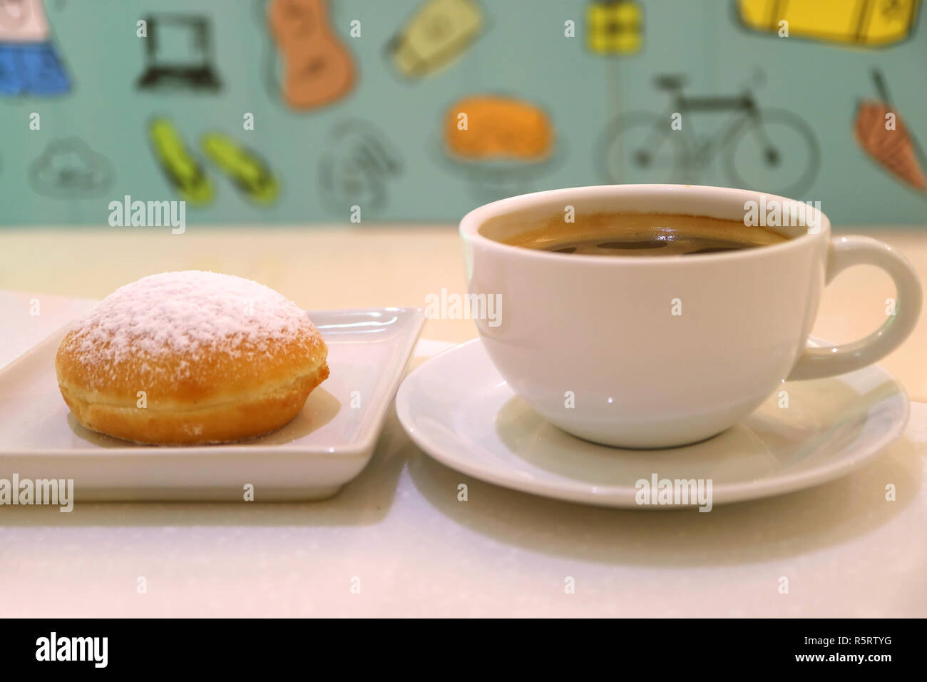 Tasse de café chaud et d'un beignet rempli de confiture de fraises avec du papier peint coloré flou en arrière-plan Banque D'Images