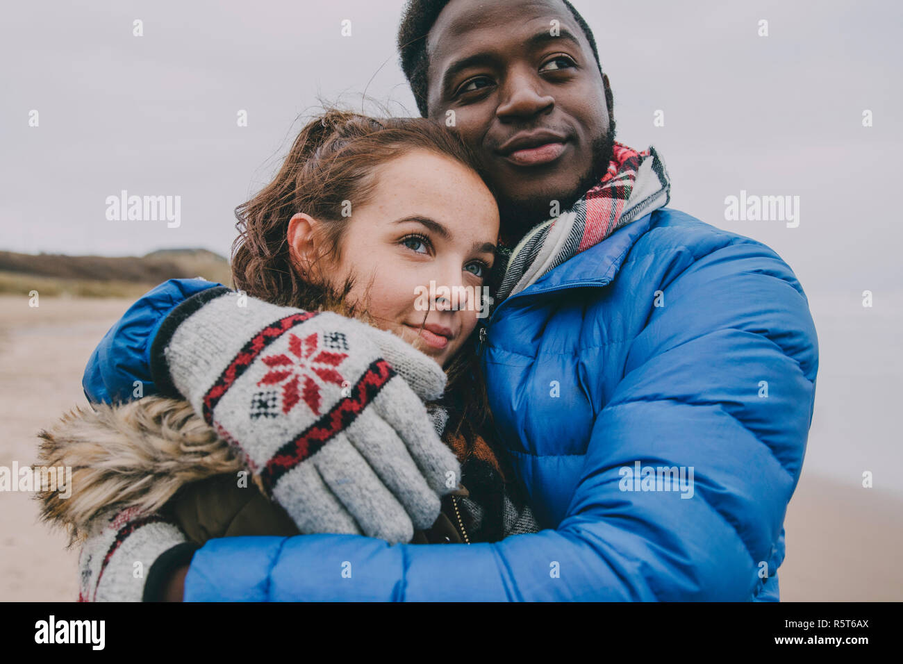 Jeune couple Hugging sur une plage d'hiver Banque D'Images