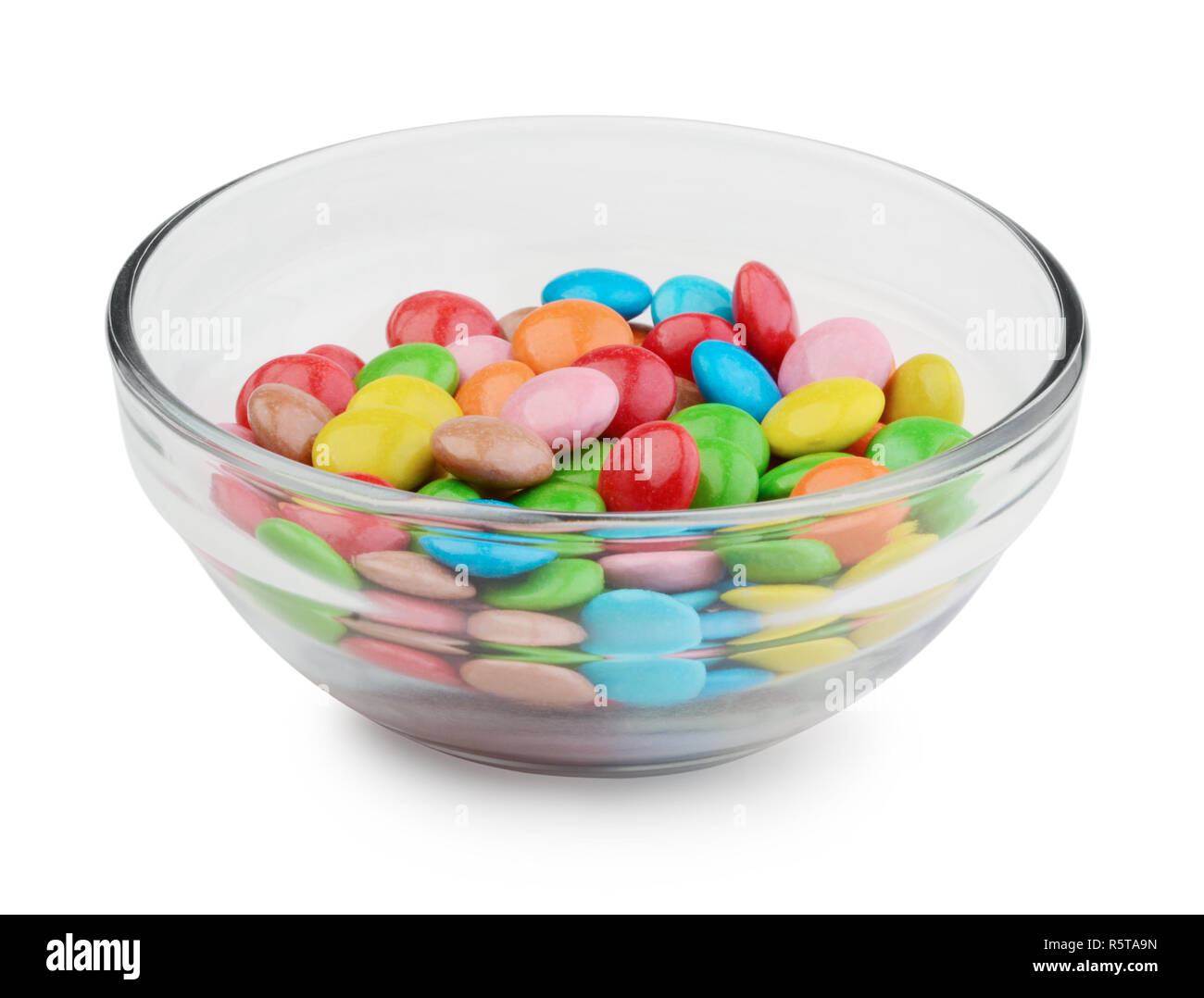 Bonbons multicolores dans bol en verre isolé sur fond blanc Banque D'Images