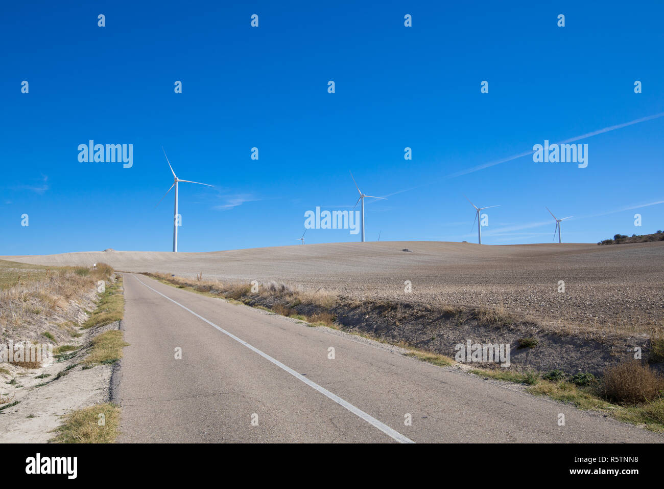 Chemin rural à côté de l'énergie éolienne éoliennes sur prairie d'hiver près de la ville de Ampudia Palencia en Espagne, Banque D'Images