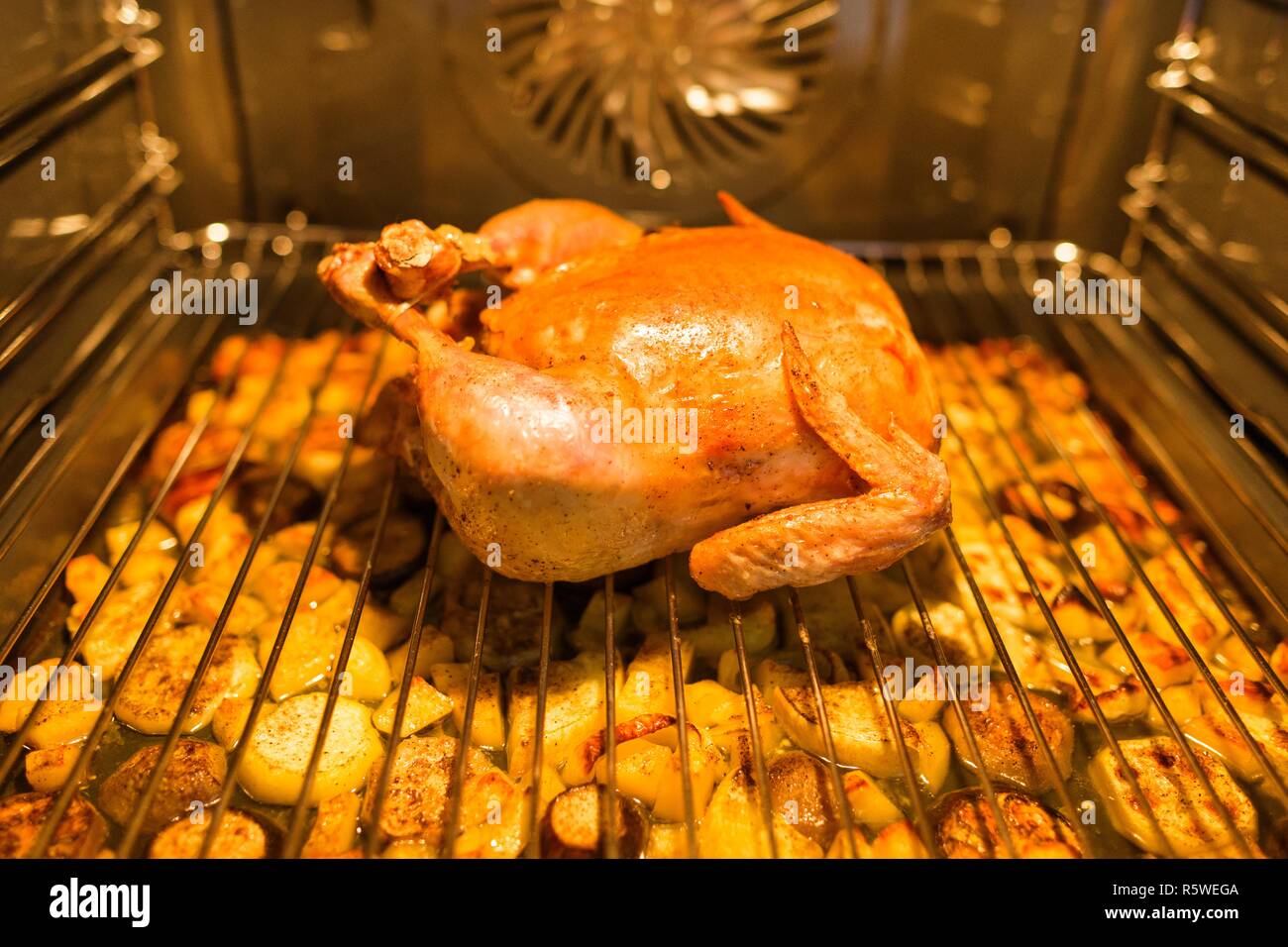 Poulet rôti au four sur la grille, sous le poulet avec les quartiers de  pommes de terre Photo Stock - Alamy