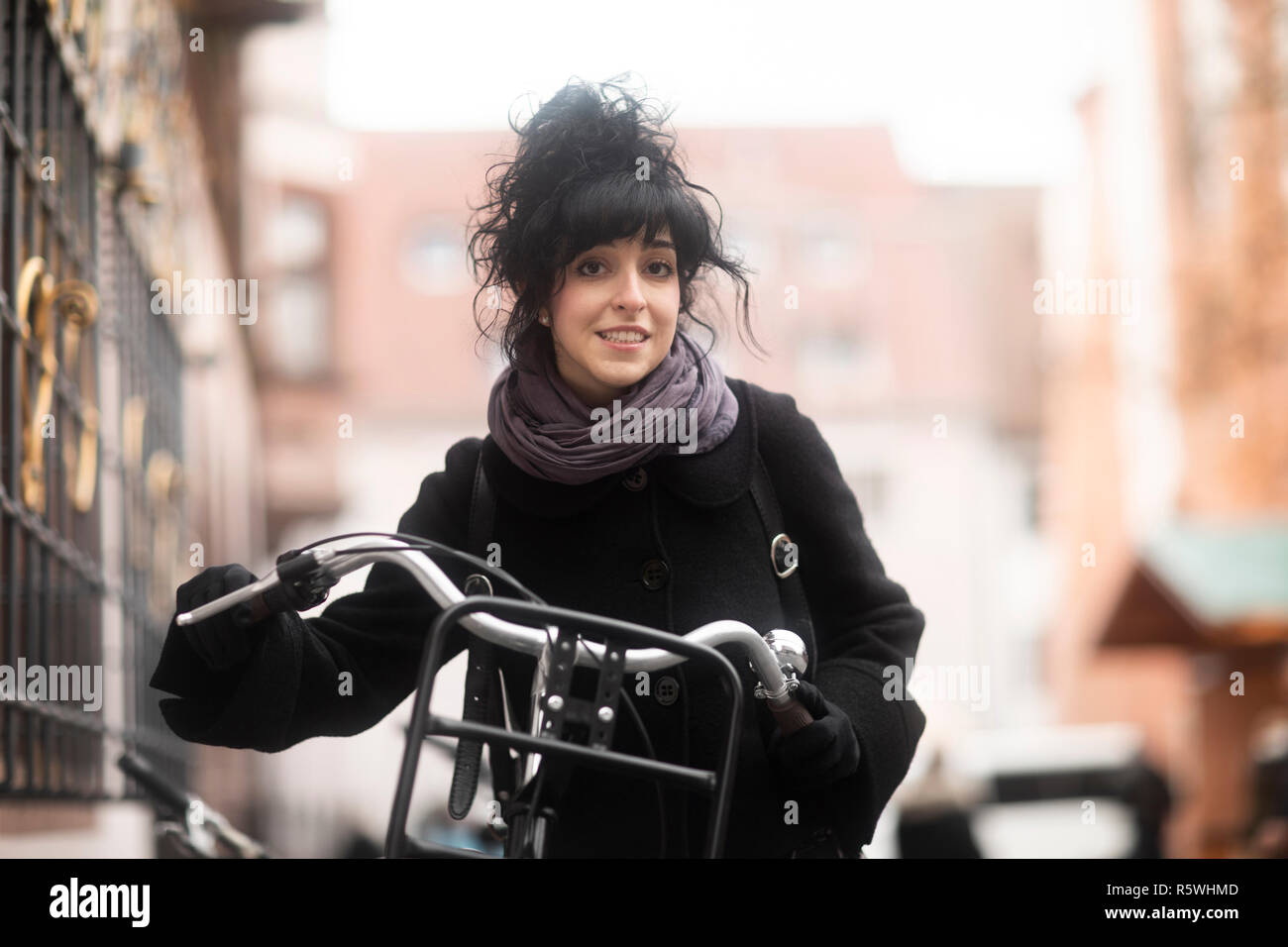 Femme debout dans la rue avec son vélo, Allemagne Banque D'Images