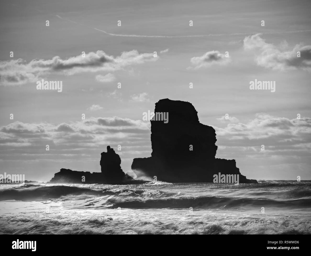 Soir nuageux sur côte rocheuse au coucher du soleil. Coucher du soleil en miroir dans l'eau de mer et de grandes marques d'érosion des roches fissurées avec l'Écosse, l'île de Sky, Talisker Bay. Banque D'Images