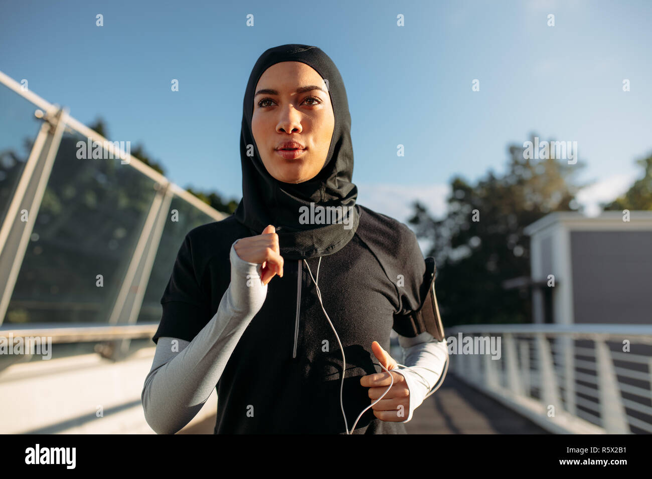 Sportive saine woman wearing hijab le jogging à l'extérieur de la ville. Femme musulmane en marche tôt le matin. Banque D'Images