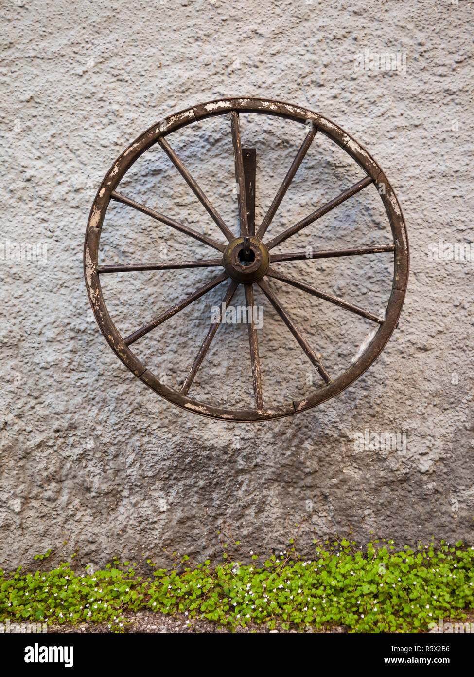 Une vieille roue de chariot affiché sur un vieux mur rustique, Autriche Banque D'Images