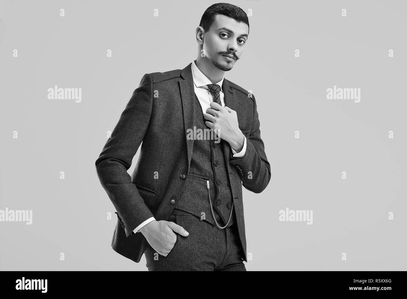 Portrait de beau jeune homme arabe confiant avec fantaisie dans moustache brun en laine combinaison complète sur fond de studio Banque D'Images