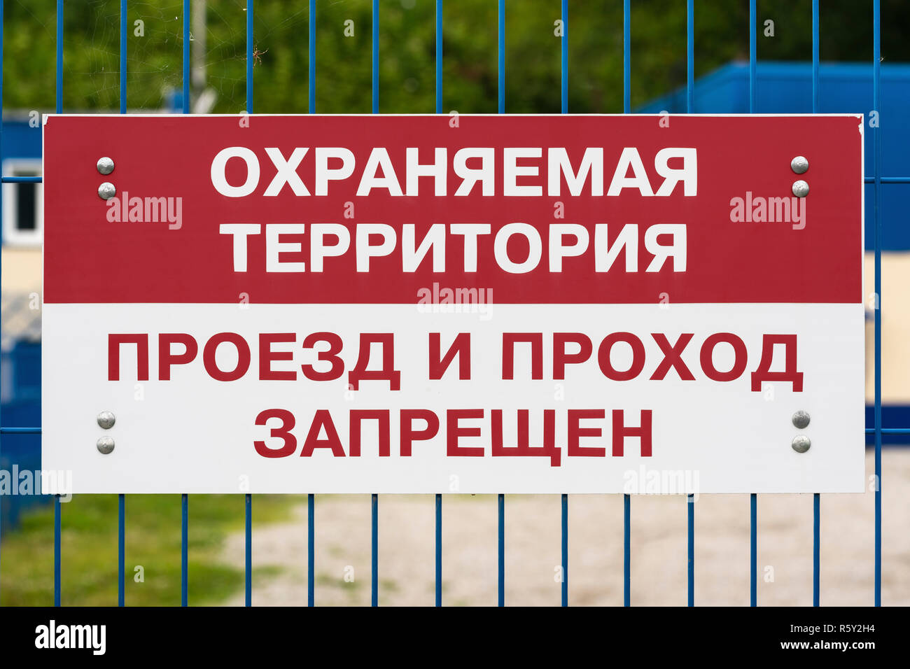 Signe d'interdiction rouge et blanc sur vert pour clôture en treillis, texte en russe : zone de protection, la marche et le passage est interdit. Banque D'Images
