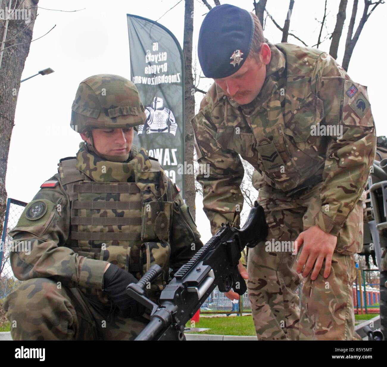 Un soldat britannique de Battle Group Pologne décrit la fonction de sa mitrailleuse à un soldat polonais 15e Brigade mécanisée à Stol DOSKONALENIA ZAWODOWEGO, une école militaire, à Gizycko, Pologne 25 avril. Le groupe tactique a participé à une exposition statique pour les élèves du secondaire de l'école au cours de la journée portes ouvertes permettant aux élèves et les citoyens polonais d'interagir avec l'unité multinationale et explorer son équipement de combat. L'unique formation d'américains, britanniques et soldats roumains sont en service avec Polish 15e Brigade mécanisée de soldats comme une force de dissuasion dans le nord-est de la Pologne Banque D'Images