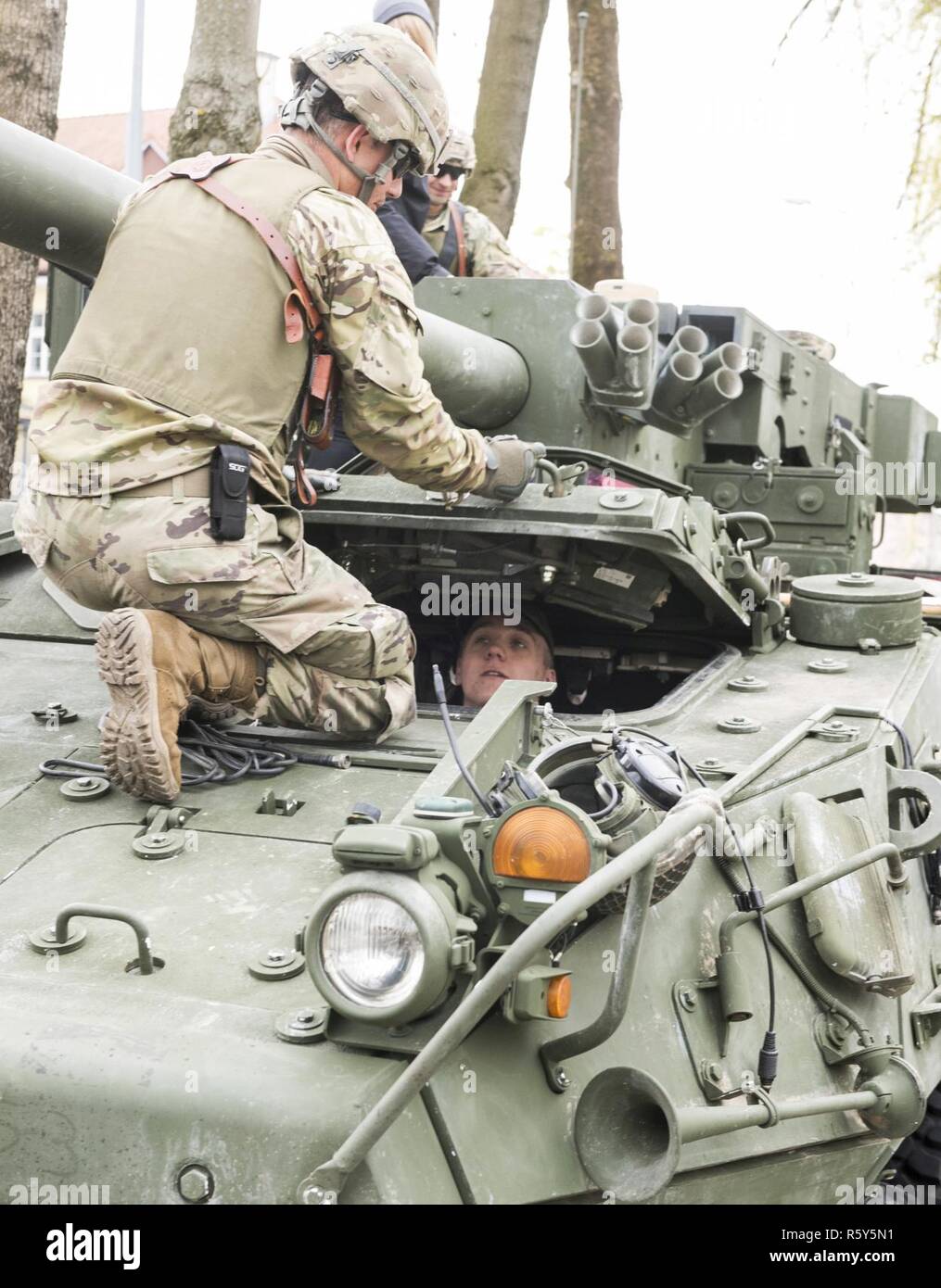 Un soldat de l'armée américaine de Battle Group Pologne ferme l'écoutille du conducteur à son Stryker afin qu'un étudiant polonais peuvent regarder à travers le périscope avant du véhicule lors d'une journée portes ouvertes à l'Stol DOSKONALENIA ZAWODOWEGO, une école militaire, à Gizycko, Pologne 25 avril. Au cours de l'événement, les étudiants et les citoyens polonais ont interagi avec l'unité multinationale et exploré son équipement de combat. L'unique formation d'américains, britanniques et soldats roumains sont en service avec Polish 15e Brigade mécanisée de soldats comme une force de dissuasion dans le nord-est de la Pologne à l'appui de l'OTAN vers l'amélioration de la présence. Banque D'Images