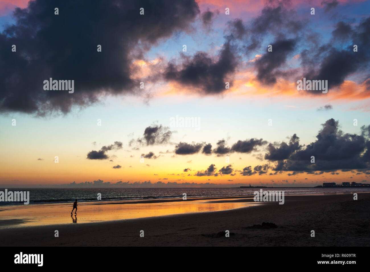 Runner sur la plage de Cadix sur l'océan atlantique dans le coucher du soleil Banque D'Images