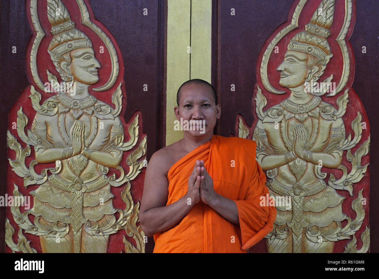 Un moine bouddhiste à Wat Mongkon (Mongkol) Nimit dans la ville de Phuket, Phuket, Thaïlande, saluant le visiteur avec un Wai, le salut traditionnel thaïlandais Banque D'Images