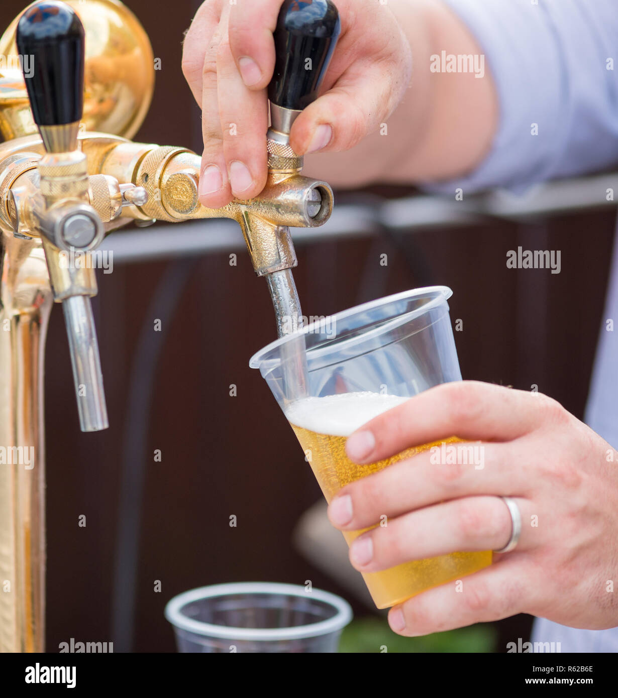 Un barman de servir la bière à un distributeur de verres en plastique Banque D'Images