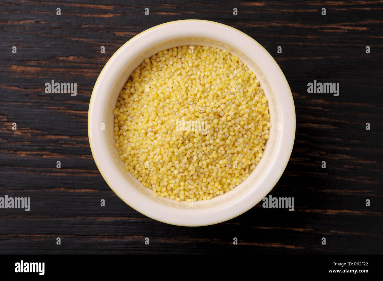 Graines de millet bio dans un bol en céramique noire en bois sur la table rustique. Le Millet peut être utilisé pour un régime alimentaire sans gluten.vue en gros plan. Banque D'Images