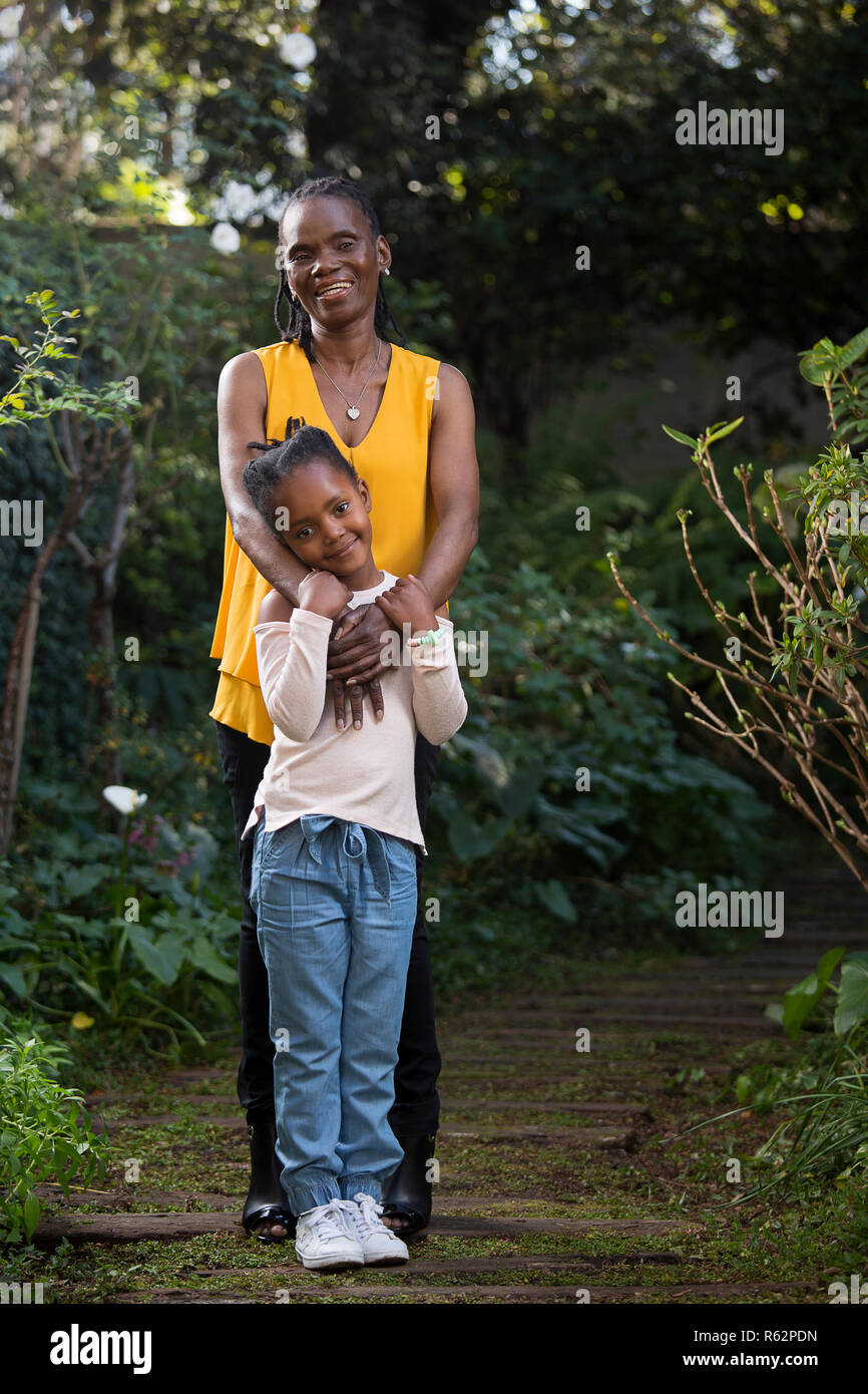 Petite-fille debout devant grand-mère dans un jardin Banque D'Images