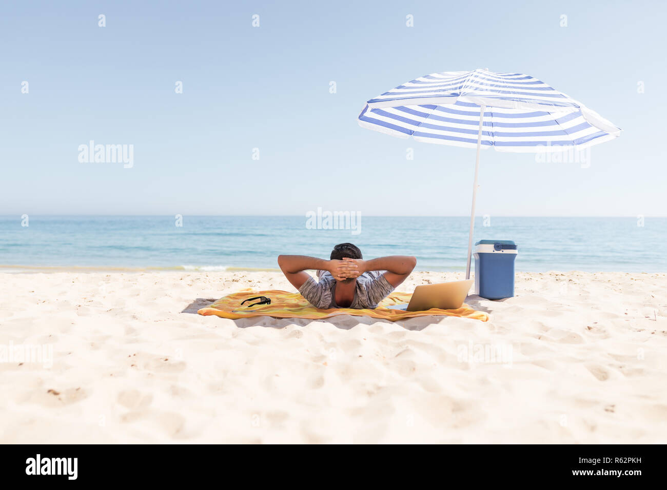 Jeune homme se repose sous un parapluie sur soleil surplombant la mer sur  la plage Photo Stock - Alamy