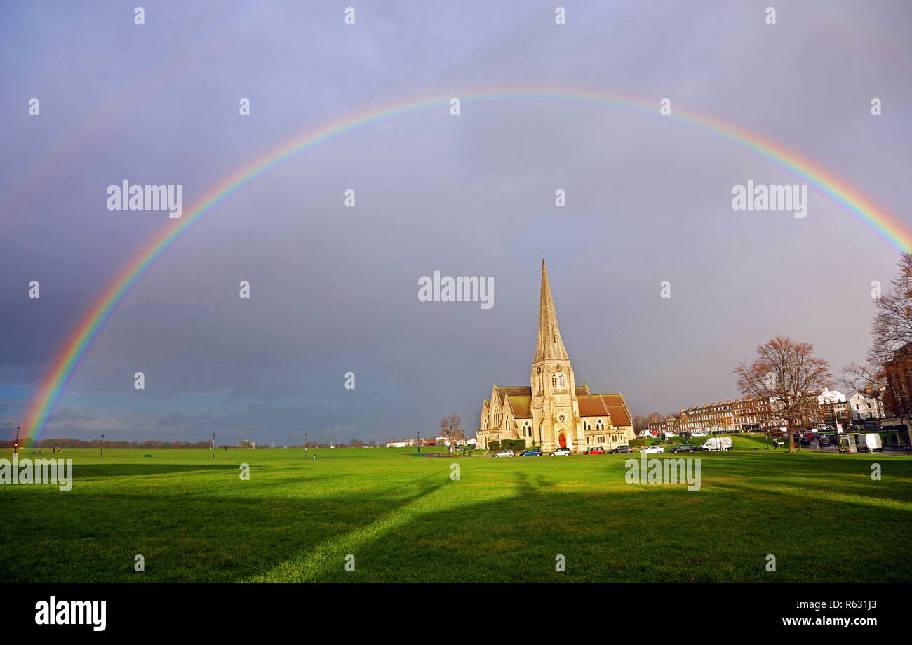 Londres, Royaume-Uni. 3 décembre 2018. Météo saisonnières - un arc-en-ciel apparaît sur All Saints' Church à Blackheath à Londres comme le soleil brise les rainclouds. Banque D'Images