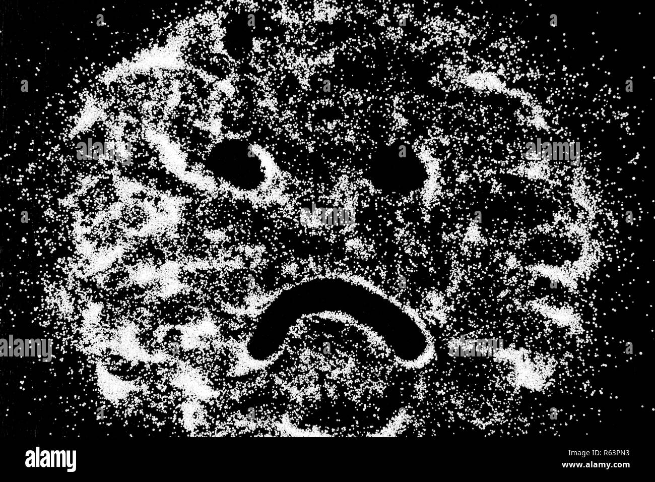 Sourire triste symbole émoticône dessin de doigt sur la neige blanche en poudre sel sur fond noir. Concept avec place pour le texte. Copier l'espace. Banque D'Images