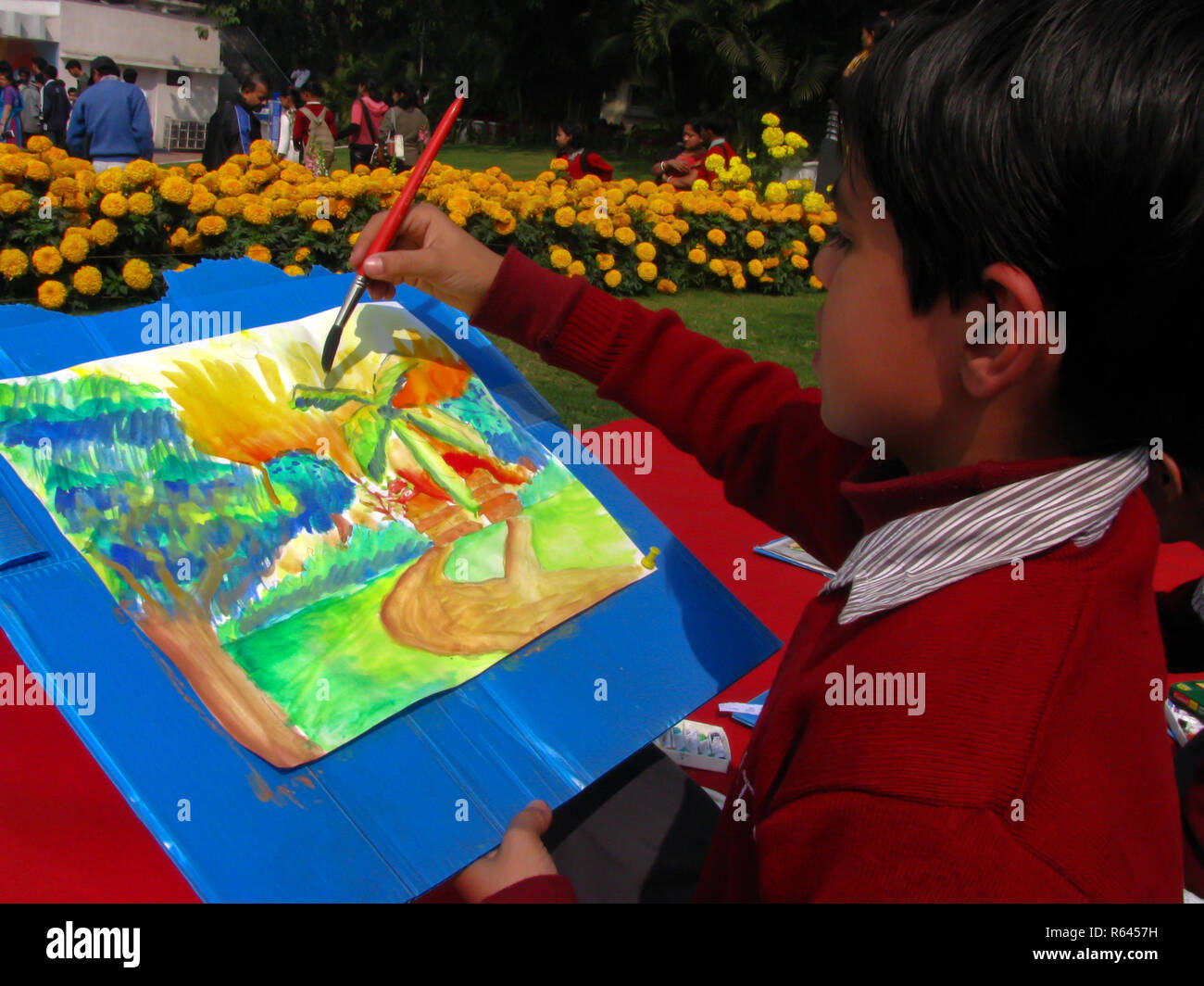 Cette photo est un gros plan d'une peinture d'un enfant pendant un concours de peinture de paysages à l'école. vous pouvez voir marigold fleurs dans l'arrière-plan Banque D'Images