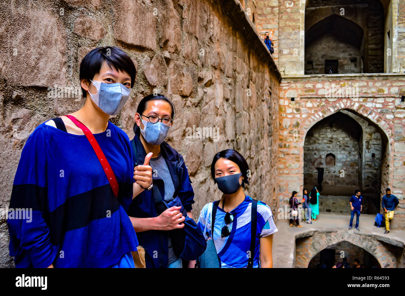 3 touristes asiatiques portant des masques se rendant sur Ugrasen ki Baoli, un monument du patrimoine mondial dans la région de Delhi, Inde, vers 2018. Banque D'Images