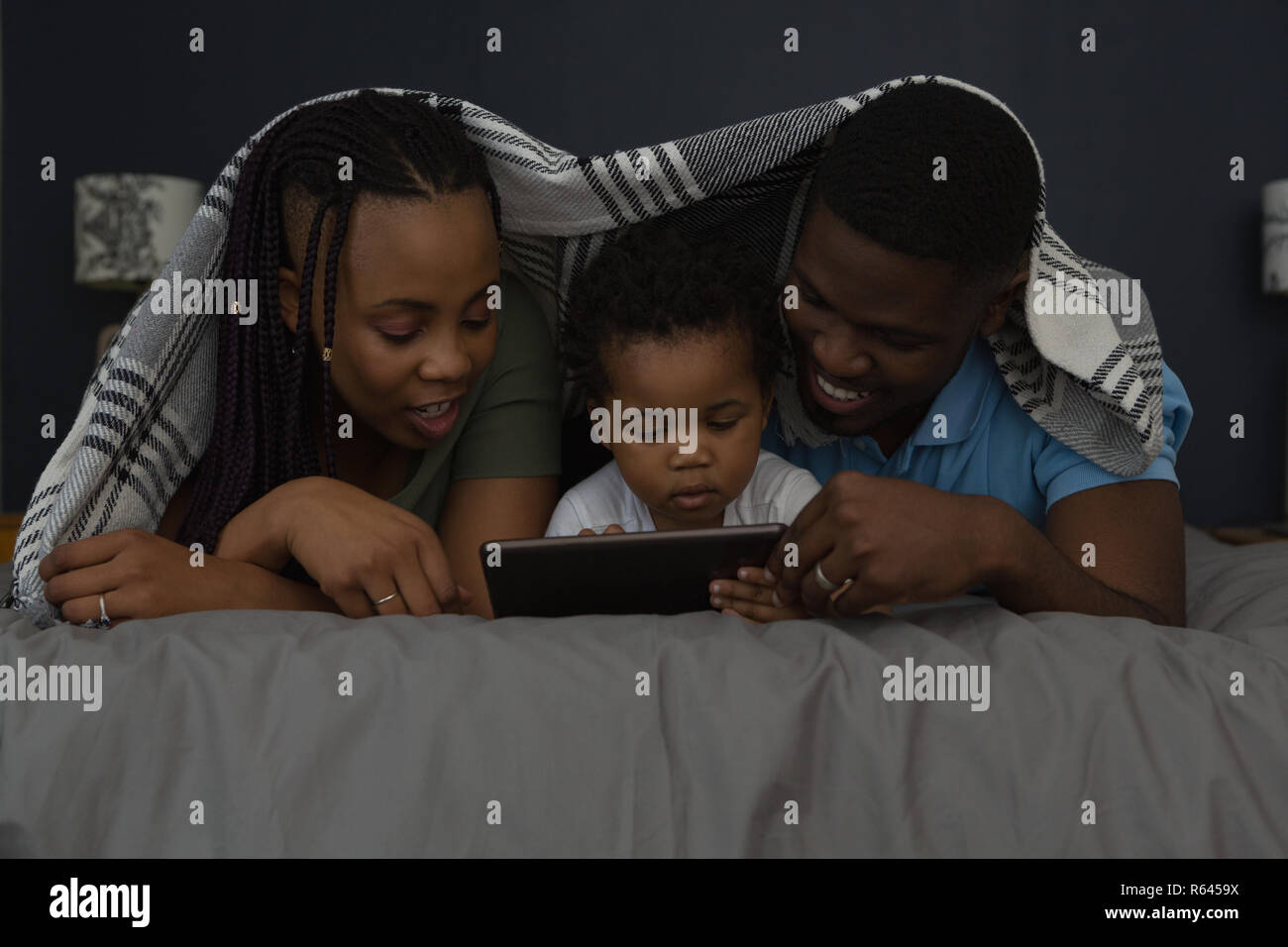 À l'aide de mobile de la famille sous le drap de lit en position couchée sur le lit Banque D'Images